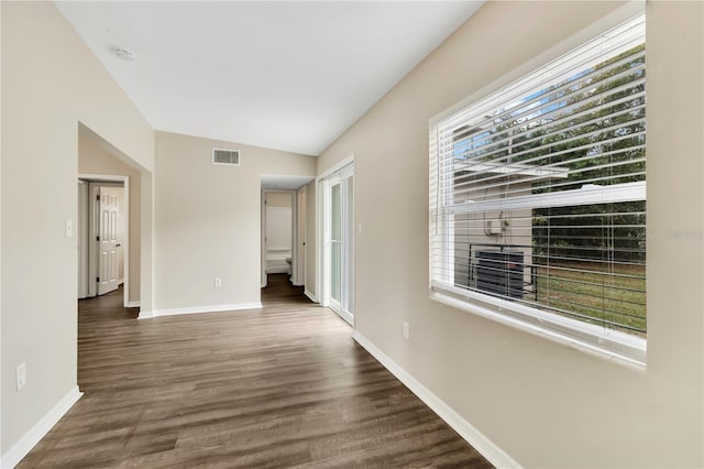 empty room featuring wood finished floors, visible vents, and baseboards