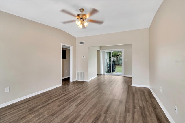 empty room with vaulted ceiling, dark wood-style flooring, visible vents, and baseboards