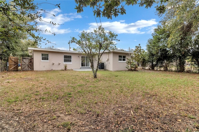rear view of property featuring a yard, concrete block siding, and fence