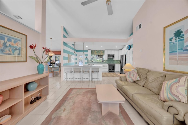 living room featuring a ceiling fan, visible vents, high vaulted ceiling, and light tile patterned floors