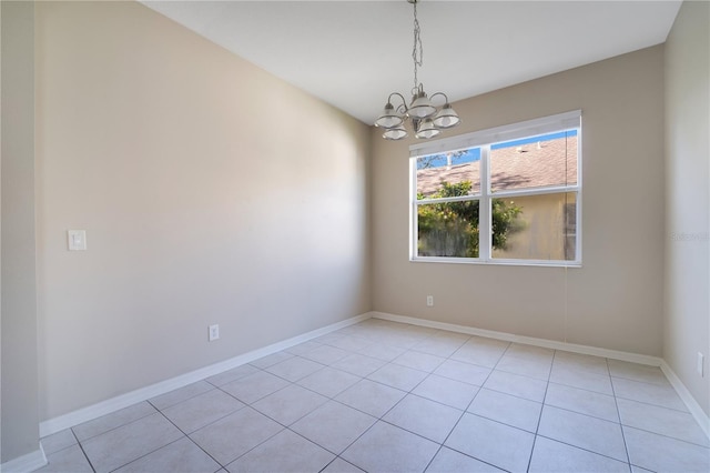 spare room with a notable chandelier, light tile patterned flooring, and baseboards