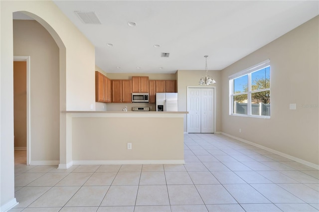 kitchen with stainless steel appliances, visible vents, a peninsula, and baseboards