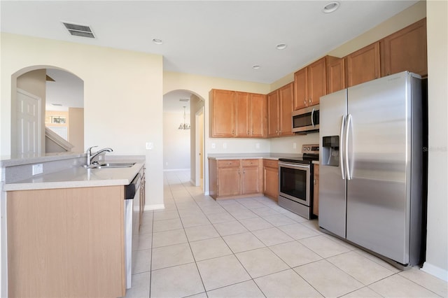 kitchen featuring light tile patterned floors, stainless steel appliances, a sink, visible vents, and light countertops