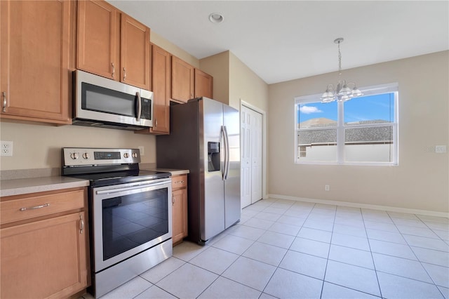 kitchen featuring light tile patterned floors, baseboards, light countertops, appliances with stainless steel finishes, and decorative light fixtures