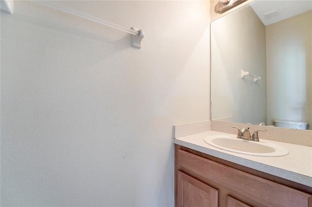 half bathroom featuring toilet, visible vents, and vanity