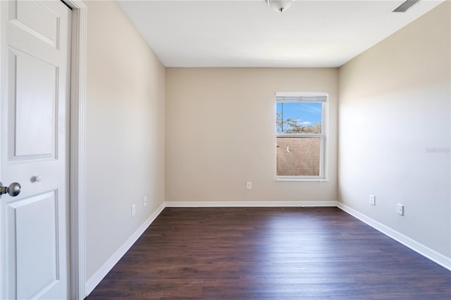 spare room featuring dark wood finished floors, visible vents, and baseboards