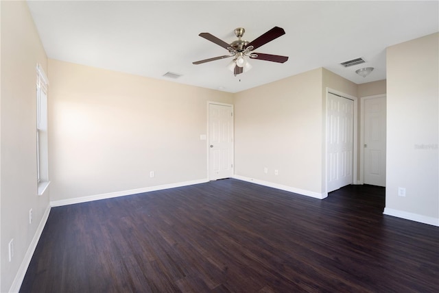 unfurnished room featuring dark wood-type flooring, visible vents, ceiling fan, and baseboards