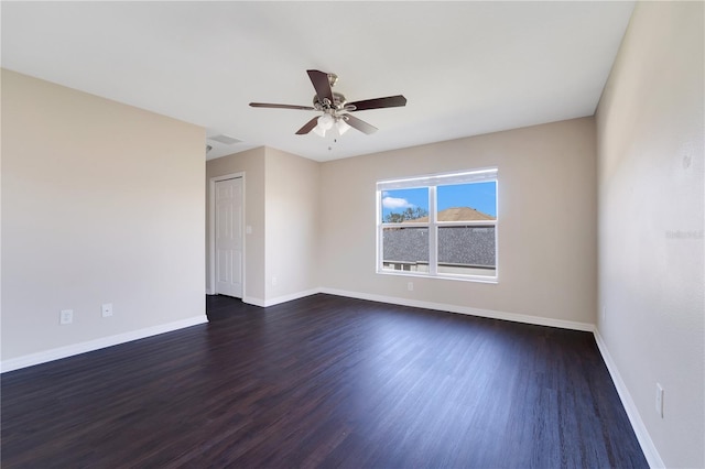 spare room with ceiling fan, dark wood-style flooring, and baseboards