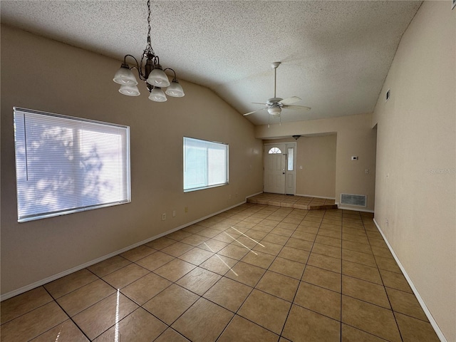 empty room with ceiling fan with notable chandelier, vaulted ceiling, light tile patterned flooring, and visible vents