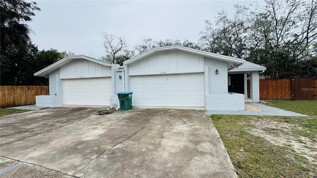 garage featuring driveway and fence