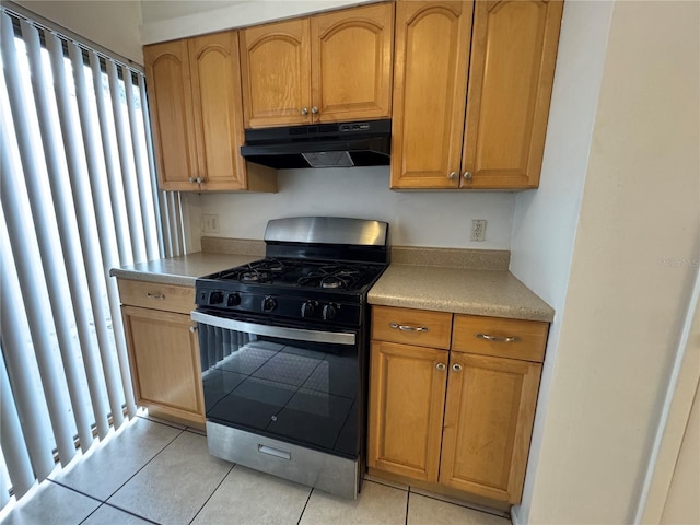 kitchen with under cabinet range hood, light tile patterned floors, light countertops, and gas stove