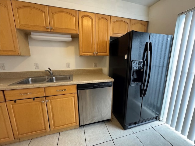 kitchen with light countertops, stainless steel dishwasher, brown cabinetry, a sink, and black fridge