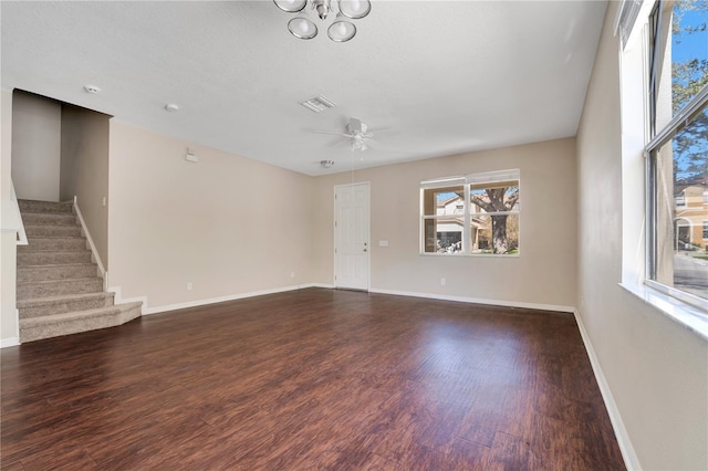 unfurnished living room featuring dark wood-style floors, visible vents, a ceiling fan, baseboards, and stairs