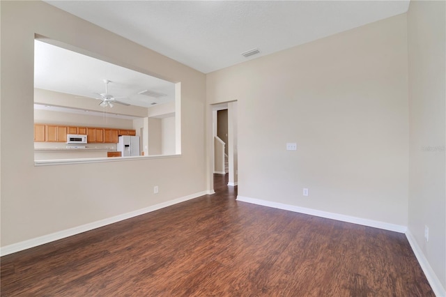 spare room featuring a ceiling fan, baseboards, visible vents, and dark wood-type flooring