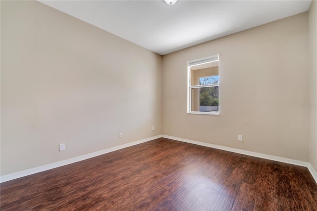 unfurnished room featuring dark wood-style flooring and baseboards