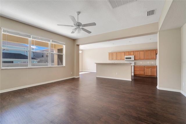 unfurnished living room featuring a ceiling fan, dark wood-style flooring, visible vents, and baseboards