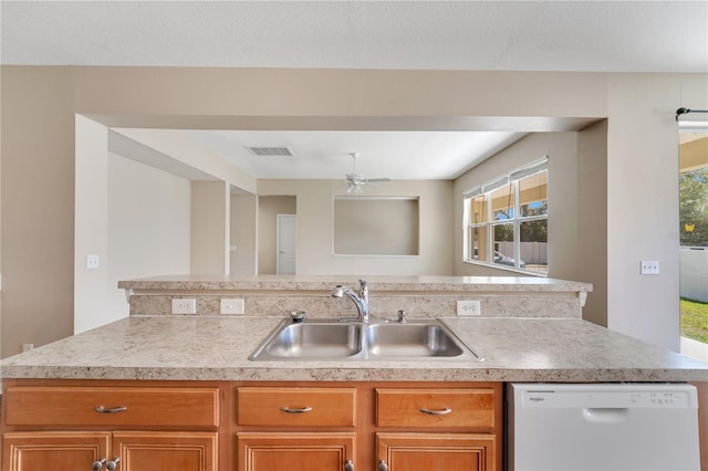 kitchen with a sink, visible vents, light countertops, dishwasher, and brown cabinetry