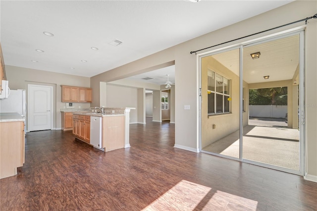 kitchen featuring light brown cabinets, white appliances, a sink, open floor plan, and dark wood finished floors