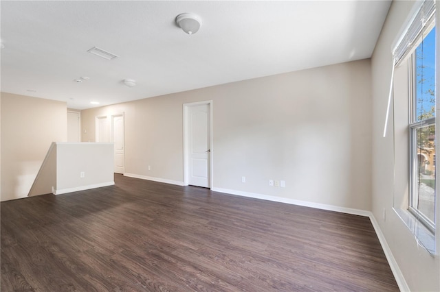 unfurnished room with visible vents, baseboards, and dark wood-style flooring