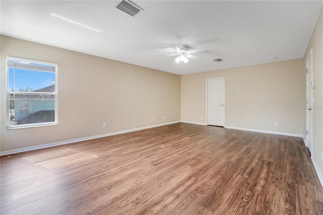 spare room with wood finished floors, visible vents, and baseboards