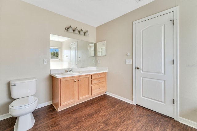 bathroom featuring toilet, baseboards, wood finished floors, and vanity