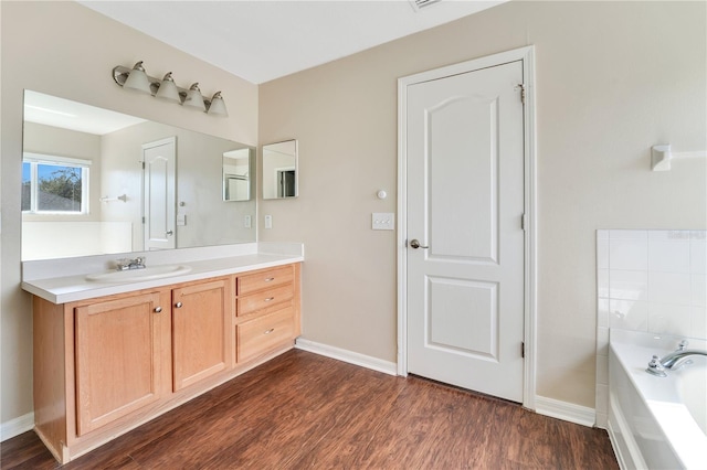 full bathroom with a garden tub, baseboards, wood finished floors, and vanity