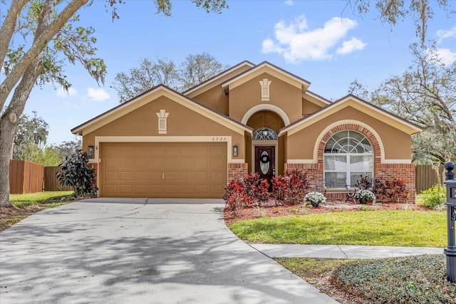 view of front of property featuring a garage, concrete driveway, brick siding, and stucco siding