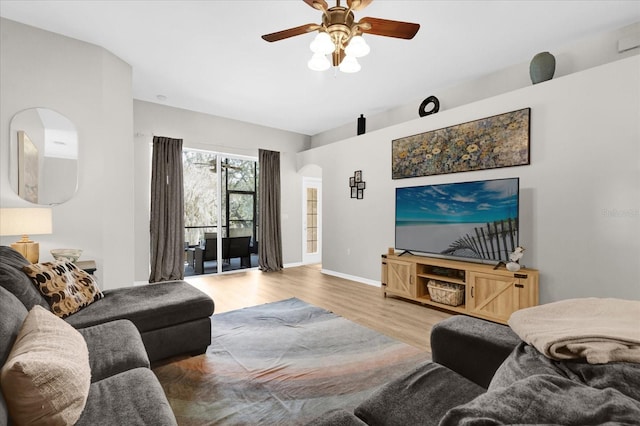 living room with arched walkways, ceiling fan, wood finished floors, and baseboards