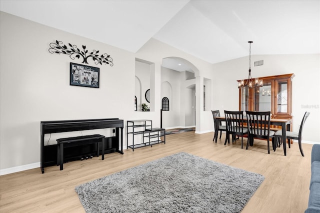 dining area with baseboards, visible vents, wood finished floors, vaulted ceiling, and a notable chandelier