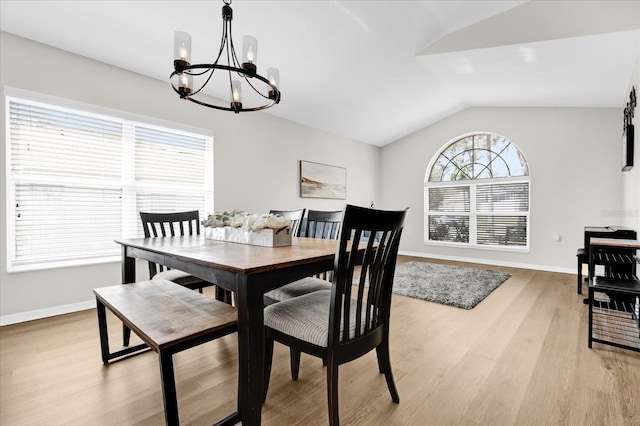 dining space featuring light wood-style floors, vaulted ceiling, baseboards, and an inviting chandelier