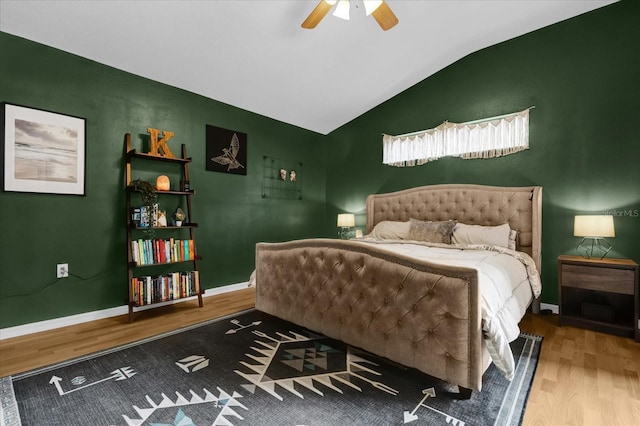 bedroom with ceiling fan, vaulted ceiling, baseboards, and wood finished floors