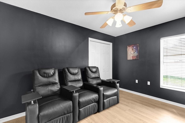 home theater room with light wood-style floors, ceiling fan, and baseboards