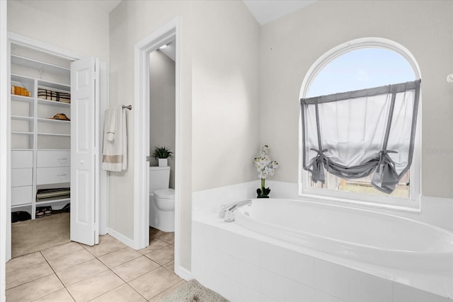 bathroom featuring a bath, a spacious closet, tile patterned flooring, and toilet