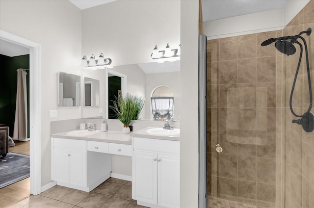 full bath featuring a shower stall, double vanity, a sink, and tile patterned floors