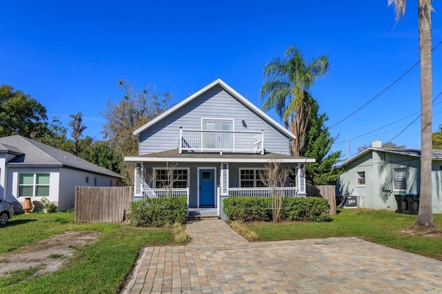 view of front of house with covered porch, a front yard, fence, and a balcony