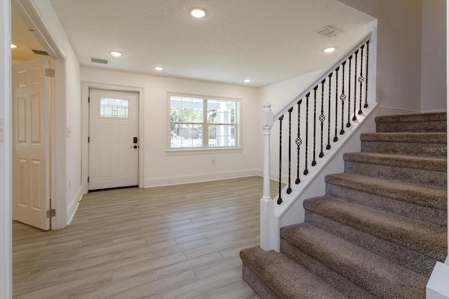 entrance foyer featuring recessed lighting, visible vents, light wood-style flooring, and a textured ceiling