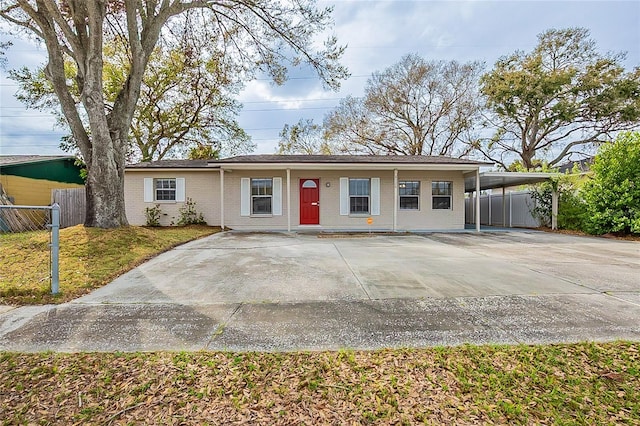 ranch-style home featuring a carport, brick siding, a front lawn, and fence