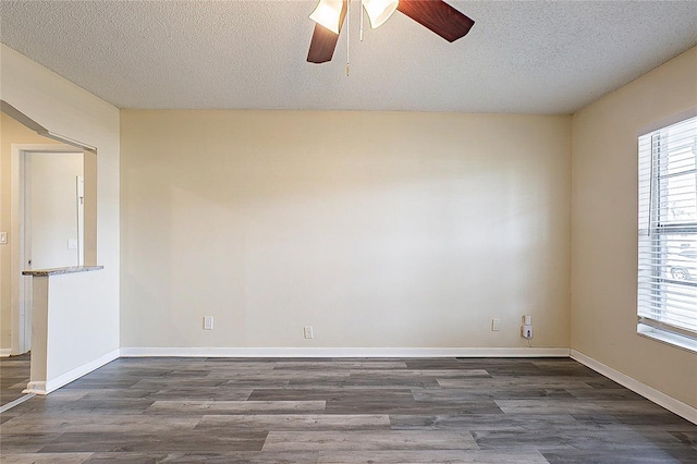 unfurnished room featuring dark wood-style floors, a textured ceiling, baseboards, and a ceiling fan