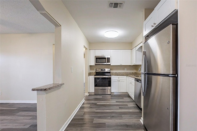 kitchen featuring stainless steel appliances, dark wood finished floors, visible vents, and white cabinets