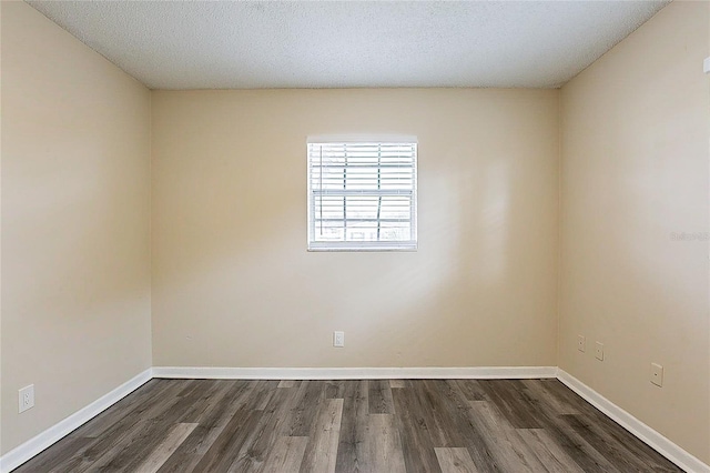 spare room with dark wood-style floors, a textured ceiling, and baseboards