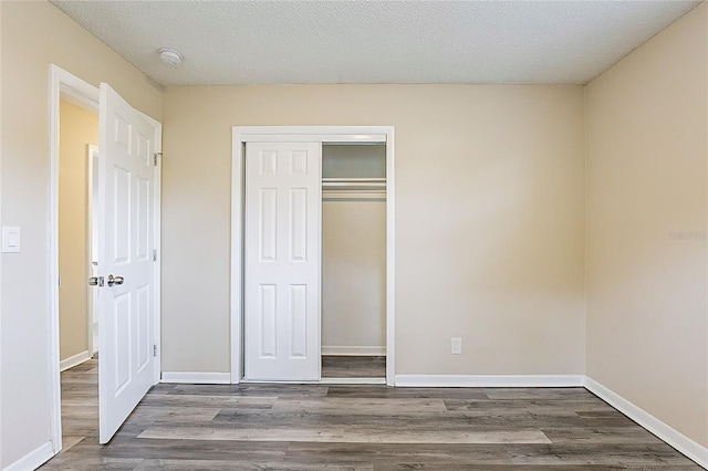 unfurnished bedroom with a closet, baseboards, and wood finished floors