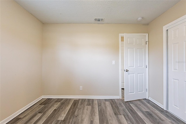 unfurnished room with dark wood-style floors, visible vents, and baseboards