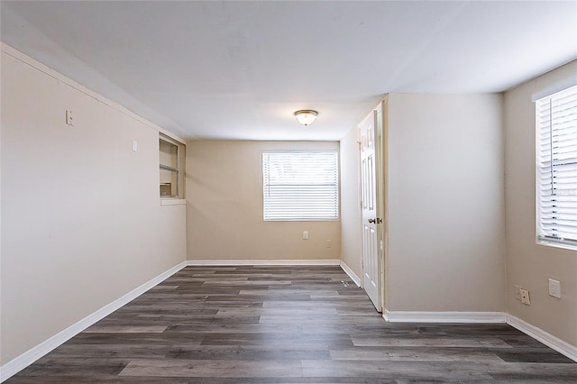 spare room featuring baseboards and dark wood-type flooring