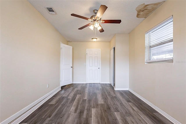 unfurnished bedroom featuring dark wood-type flooring, a closet, visible vents, and baseboards