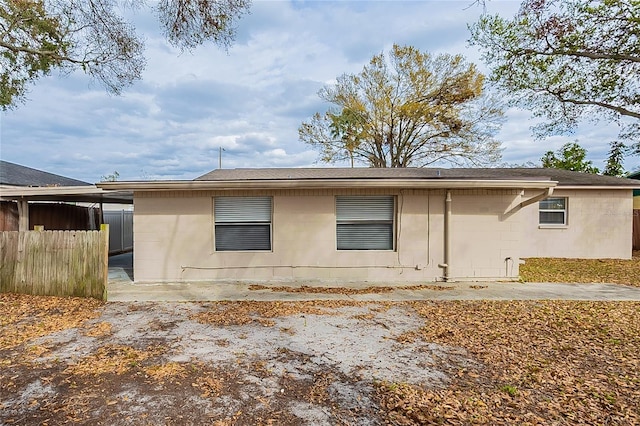 view of property exterior with a patio area, concrete block siding, and fence