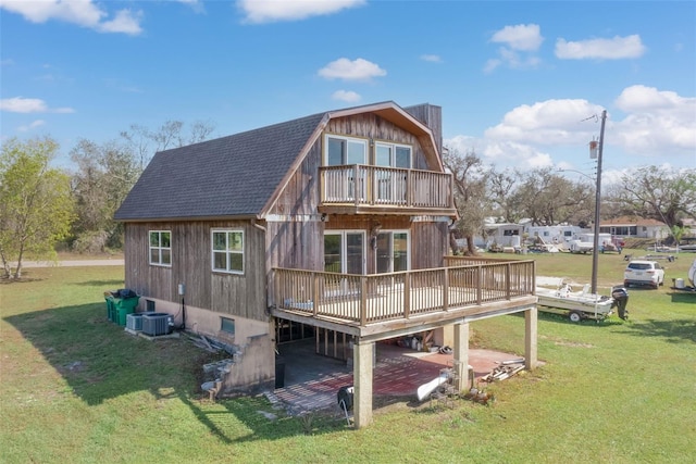 rear view of house with roof with shingles, a lawn, a gambrel roof, a deck, and a balcony