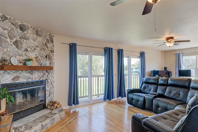 living room with light wood-type flooring and a stone fireplace