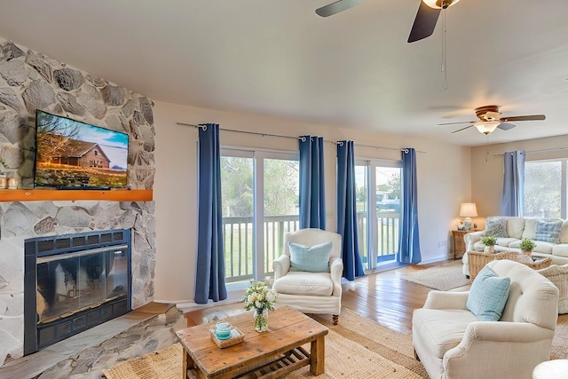 living area with baseboards, a fireplace, and light wood-style floors