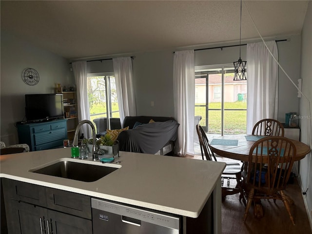 kitchen featuring a sink, decorative light fixtures, stainless steel dishwasher, open floor plan, and light countertops