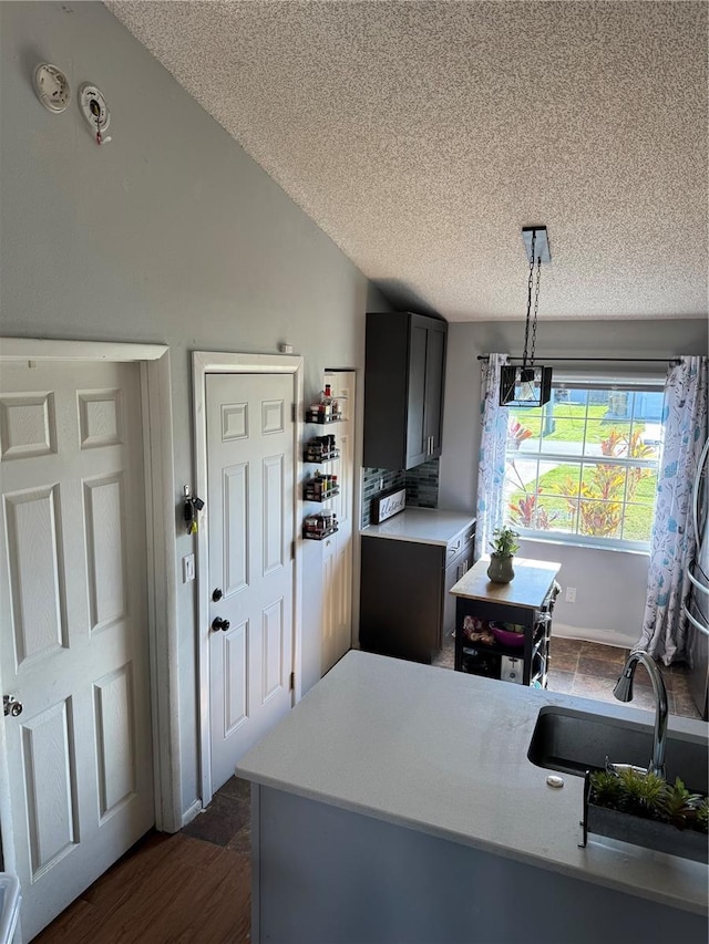 kitchen featuring a sink, decorative light fixtures, a textured ceiling, light countertops, and dark wood-style flooring